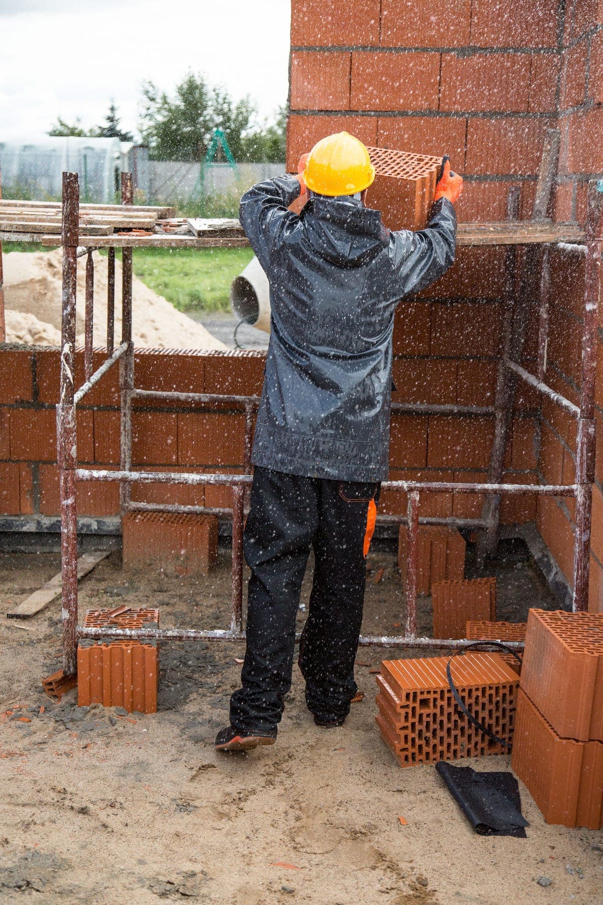 Maçon casqué disposant des briques sur un chantier